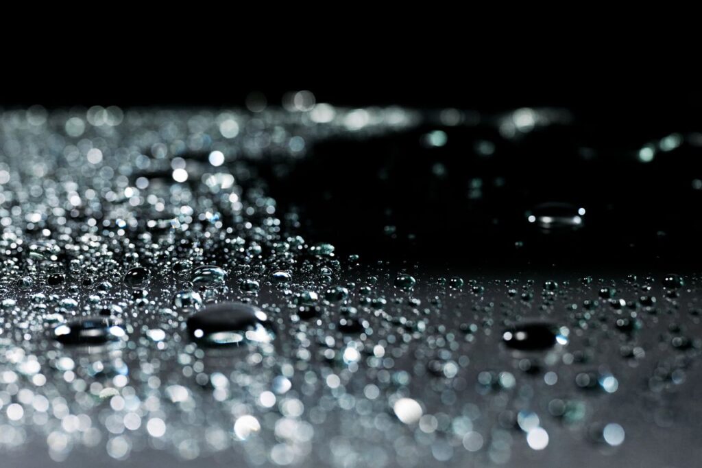 pexels photo 9667795 9667795 A dramatic macro shot highlighting water droplets on a reflective surface, capturing light and shadow.